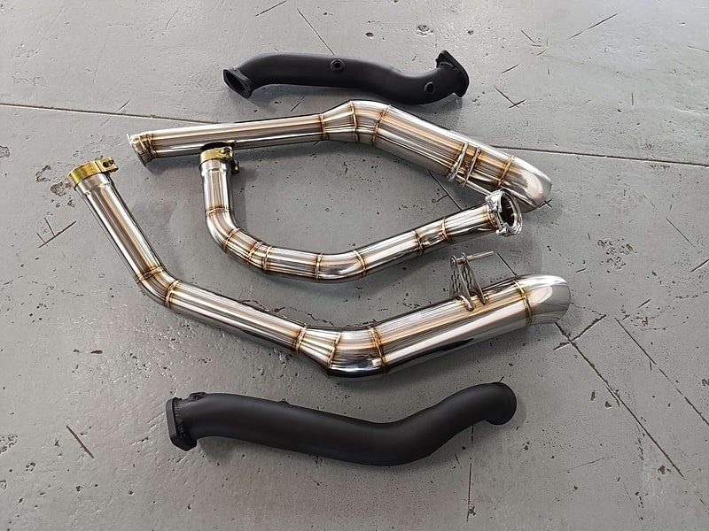 A complete stainless system laid out beside the original exhaust