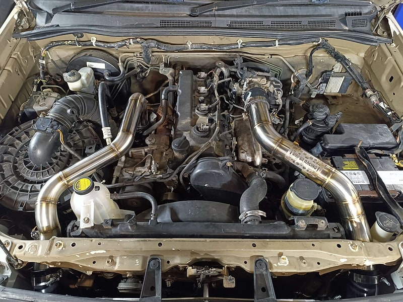 Custom polished stainless boost pipes installed in an engine bay